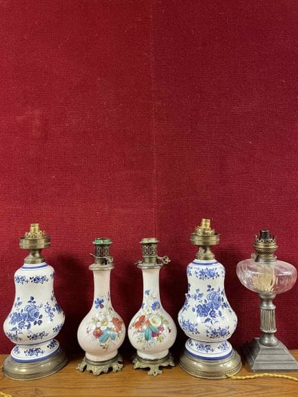 Suite de cinq lampes à pétrole en porcelaine et ve