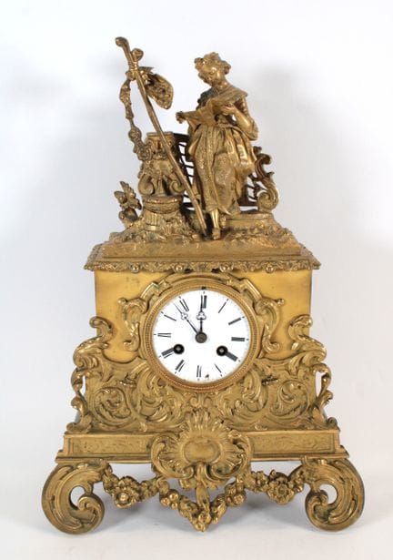 A chiseled and gilded bronze clock topped by a she
