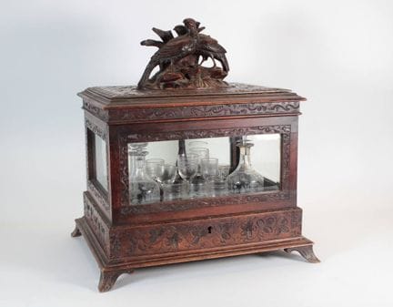A carved wooden liquor cabinet with beveled glass,