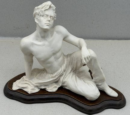 Figurine représentant un jeune homme assis, sur un