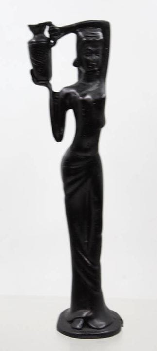 Escultura oscura de una mujer de pie que lleva una
