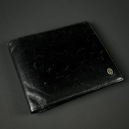 卡地亚
黑色皮革钱包，镶嵌品牌标志
10 x 11 厘米
（有细微划痕）