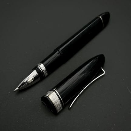 OMAS
黑色树脂圆珠笔，笔身环绕镀银的金属圈，刻有希腊式蜿蜒纹饰
（有磨损痕迹）
随笔附带一个Om