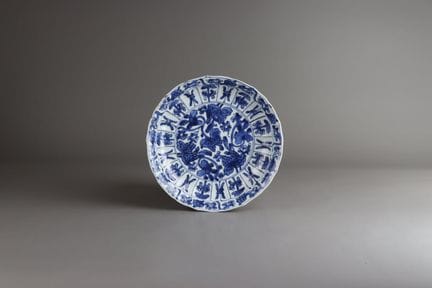 一套四只青花花瓣镶板纹盘，康熙四件套，盘体呈浅圆形，边缘饰有叶纹，盘心绘有开花枝条，周围环绕着镶板，