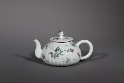 一件“玫瑰家族”风格的花卉茶壶及壶盖，19世纪。壶身呈紧凑的球形，表面饰有细腻的肋纹，配有弧形壶嘴和