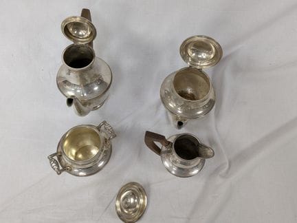 一套镀银的金属与木质餐具，包括：茶壶、咖啡壶、奶壶和糖罐，尺寸为10至18厘米。（镀银层已脱落）