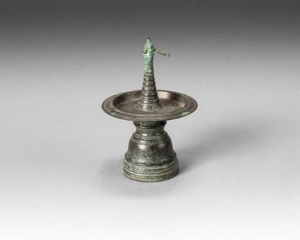 Candelabro de bronce con pátina marrón, sobre una 