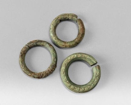 Three bronze bracelets with a green patina, decora