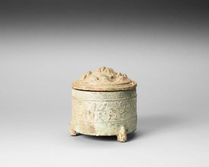 A three-legged terracotta incense burner with gree