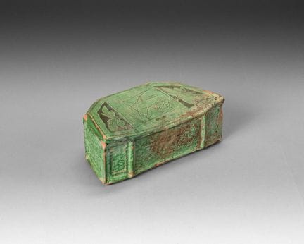 A half-moon-shaped pillow made of green-glazed ter