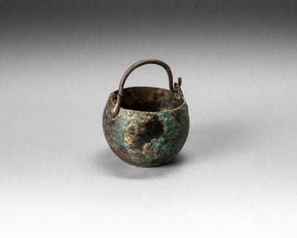 A spherical bronze and silver cauldron with a flat
