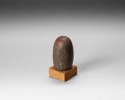 Polished stone lingam adorned with a tilak made of