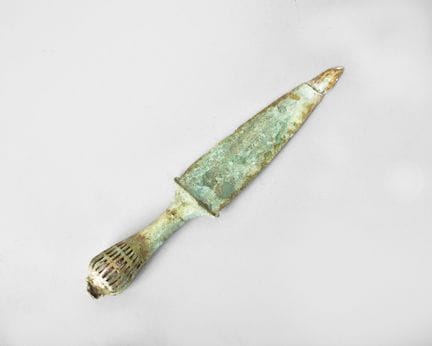 Daga de bronce muy corroída con pátina verde; el m
