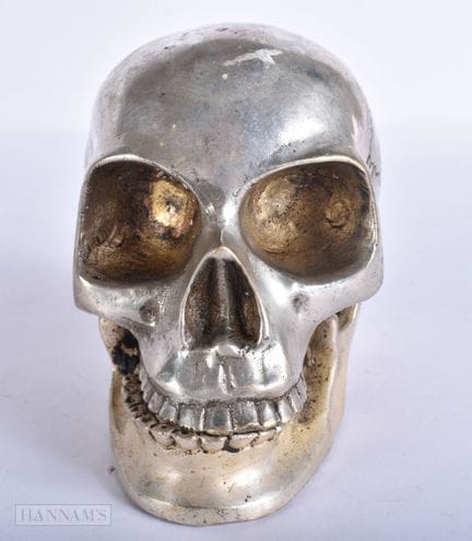 EIN SILBERFARBENE TOTENKOPF. 14 cm. 14 cm.