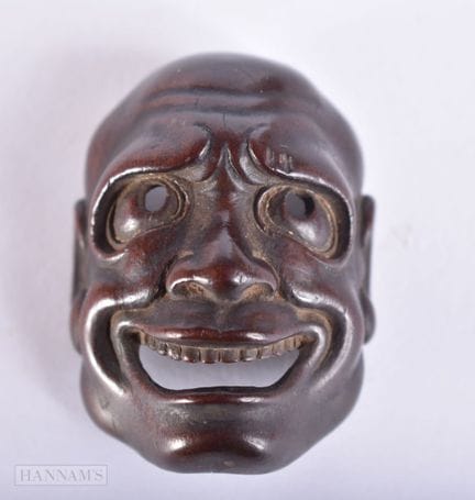 Una máscara de madera tallada de estilo netsuke, d