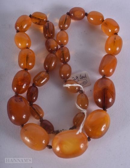 UN COLLIER EN AMBRE COMPOSÉ DE VINGT-NEUF PERLES. 