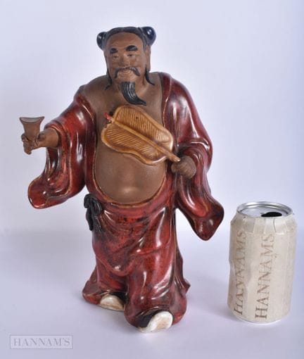 EINE CHINESISCHE SHIWAN-FIGUR AUS STEINGUT MIT FLA