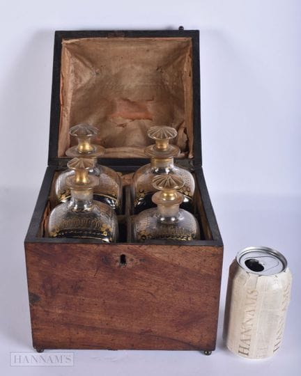 EIN SET AUS VIER GLASDEKANTERN IN EINEM MAHAGONI-K