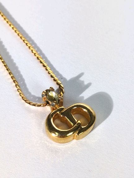 CHRISTIAN DIOR 
Anhänger aus Metall 
Signiert 
Län