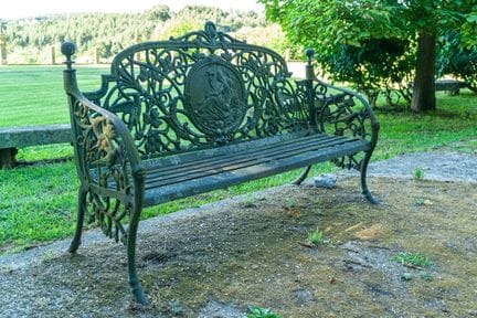 Ein Paar Gartenbänke aus Gusseisen, grün lackiert.