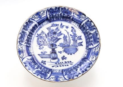蓝白彩釉圆形陶盘，中央饰有花束图案，周围环绕着花卉与枝叶纹样，覆盖整个盘面
归因于代尔夫特，18世纪