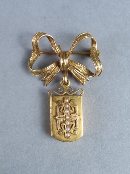 Broche de revers formée d'un noeud et d'un médaill