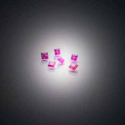 Set aus sechs quadratischen Rubinen auf Papier. 
G