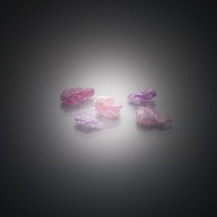Set aus fünf rohen rosa Spinellen auf Papier. 
Vie