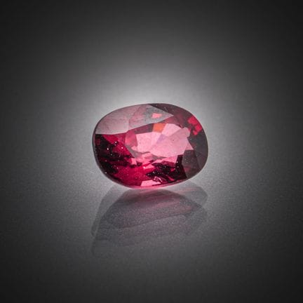 Grenat rhodolite rose violacé ovale sur papier.
Po