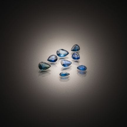 Set of eight pear-shaped sapphires on paper. 
Weig