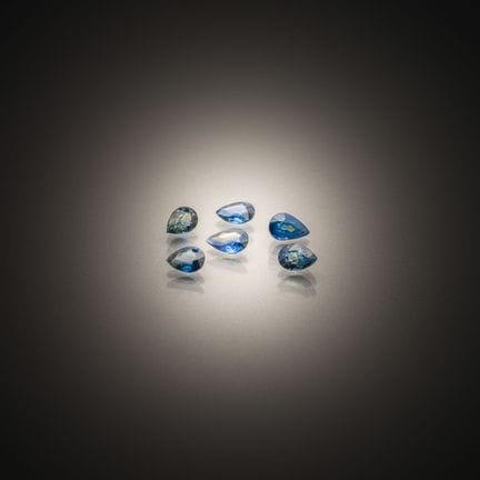 Set of six blue/green pear-shaped sapphires on pap