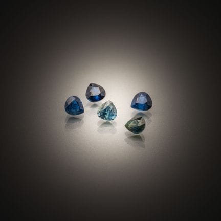 Set of five pear-shaped sapphires on paper. 
Weigh