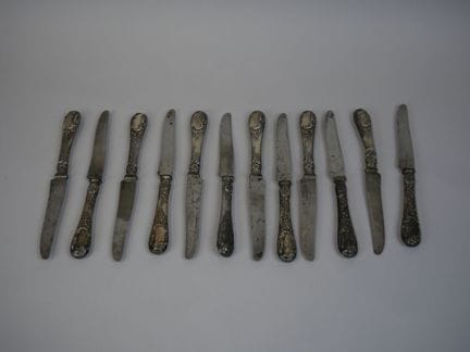 一套12把950千分之一纯度包银甜点刀（米涅瓦印记），刀柄饰有洛可可风格纹样并镌刻MP字母组合，刀身