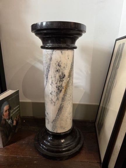 A column-shaped stool made of white marble with gr
