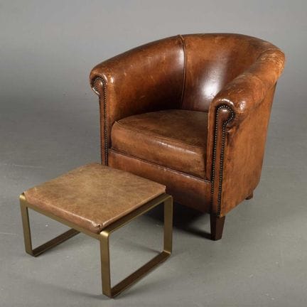 A TRADITIONAL LEATHER CLUB ARMCHAIR 
in brown, mea