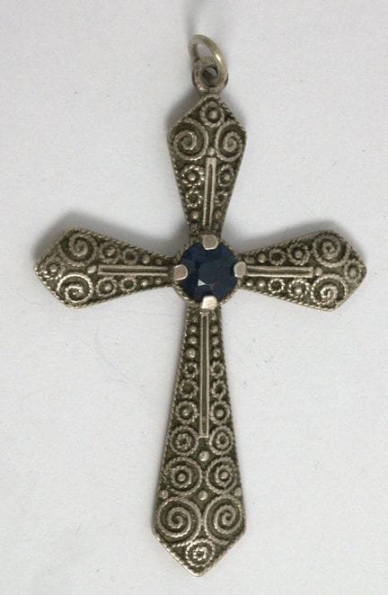 Cross pendant with a blue gemstone in the center. 
