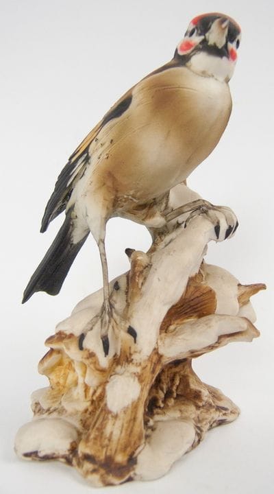Figura de porcelana de un jilguero posado en una r
