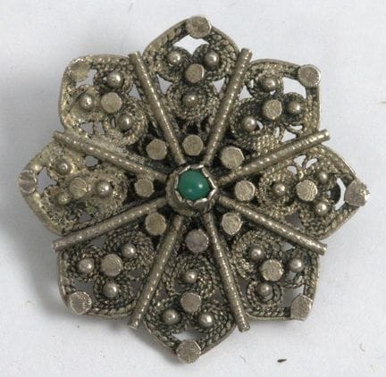 Floral brooch with a green stone in the center; ha