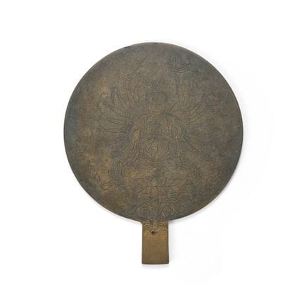 Un espejo de mano de bronce con la figura fundida 