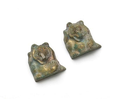 Un par de adornos de bronce dorado con forma de os