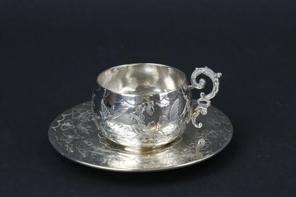 Taza y platillo de plata con decoración grabada de