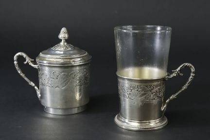 银镶边茶杯，配有可拆卸式银制茶滤装置，杯身饰有乐器奖杯图案，背景为藤蔓纹样和扭纹装饰。
第一级米涅瓦