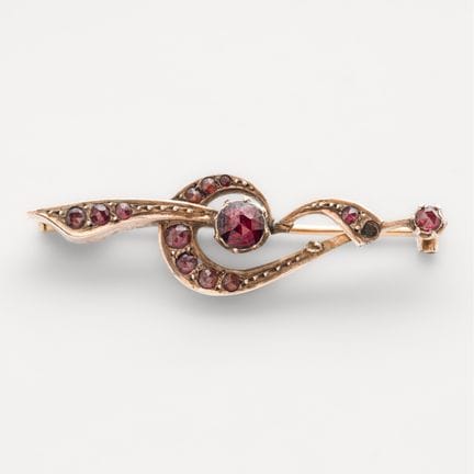 Broche en oro con banda y roleo de granates talla 