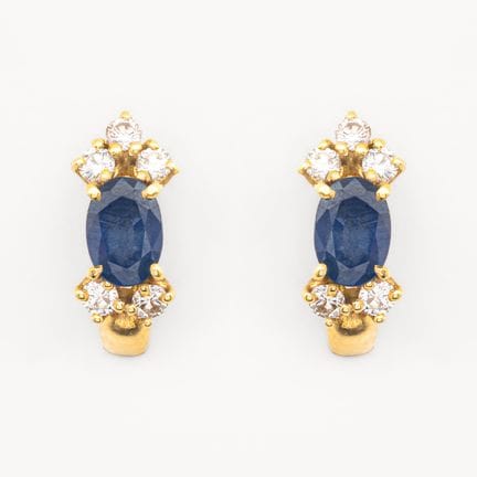 Gold earrings featuring an oval-cut blue sapphire 
