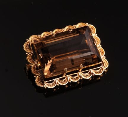 18-karat yellow gold (750) brooch, featuring an em
