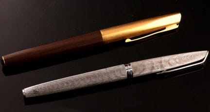 两支钢笔，笔身分别为镀银的金属、金色和棕色金属材质。
笔尖采用18K（750）黄K金和白K金制成。