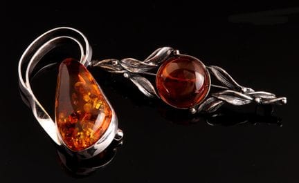 Two silver-set brooches: one features a foliage mo