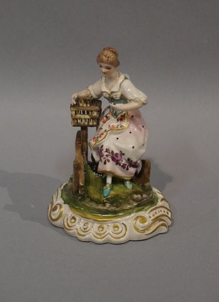 Polychrome Keramikfigur: „Sitzende junge Frau am K