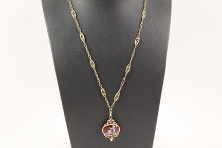 18K（750）黄金与珐琅吊坠，描绘了一位在红色背景上敲响警钟的小天使，配以18K（750）黄金镂空