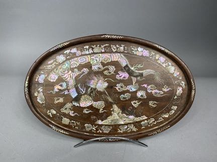 越南 约 1900 年
椭圆形木制托盘，饰以螺钿镶嵌，描绘了一条龙和一条鲤鱼在波涛中嬉戏，周围环绕着